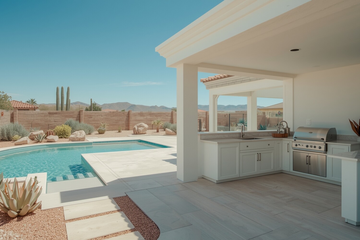 A luxury outdoor kitchen in a modern Las Vegas backyard with stone counters, stainless steel appliances, and desert landscaping.