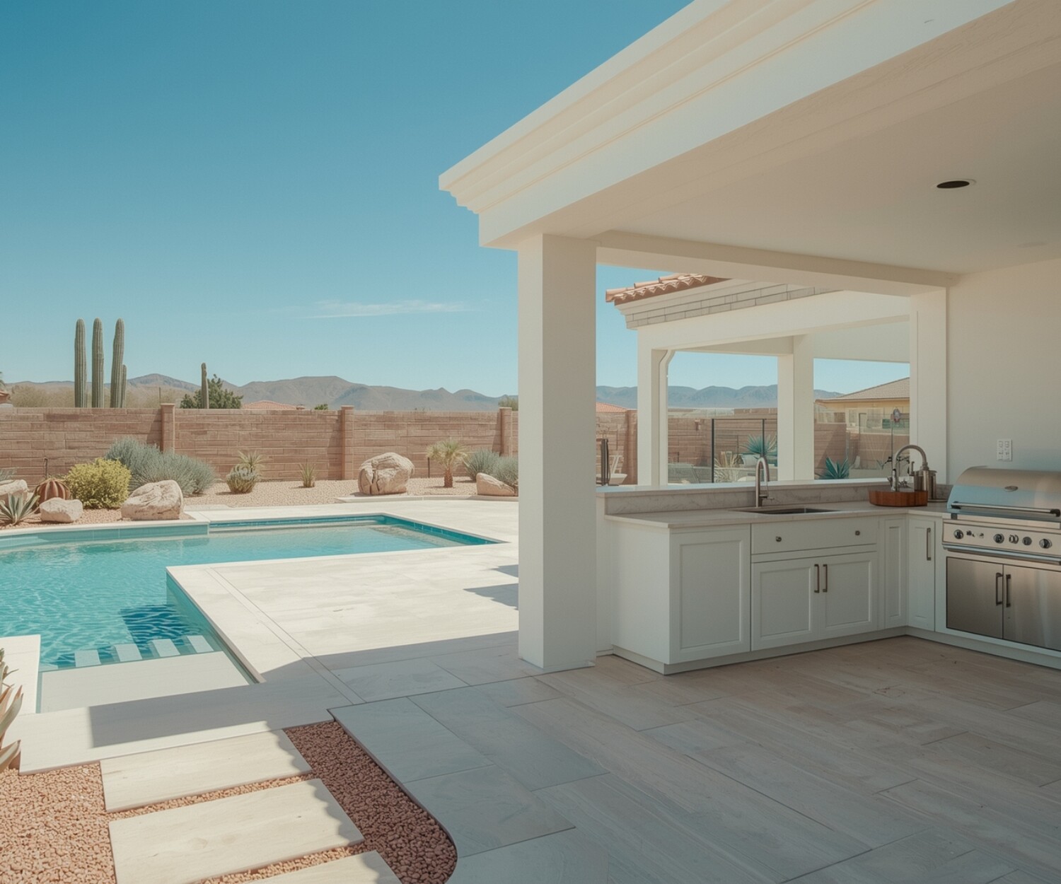 A luxury outdoor kitchen in a modern Las Vegas backyard with stone counters, stainless steel appliances, and desert landscaping.